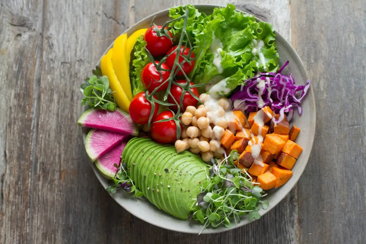 A bowl of vegetables, chickpeas and avocado on a wooden table